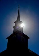 sunburst behind a silhouette of a church steeple 