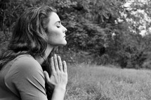 a woman praying outdoors