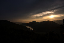 sunburst over mountains and lake at dusk 