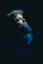 man with a thick beard looking up in darkness