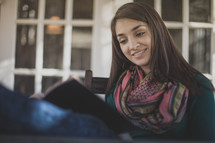 A young woman smiling and reading the Bible