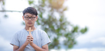 a young man praying holding a cross 