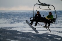 snow boarder and skier on a ski lift chair