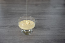 condensed milk in a transparent glass bowl on a wooden background