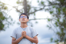 a young man praying outdoors 