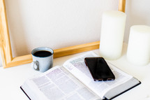 cellphone on the pages of a Bible and coffee cup 