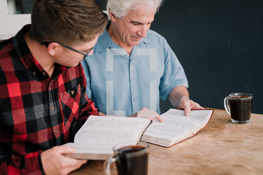 mentor reading a Bible with a man at a Bible study 