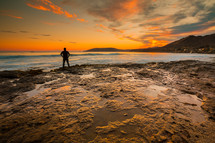 a man standing on a shore at sunrise 