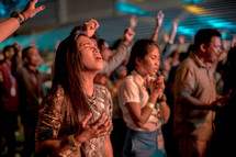 people praying and singing at a concert 