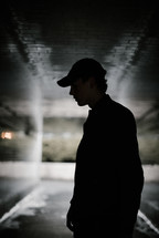 a man standing in a dark urban tunnel 