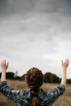 a woman with raised hands standing in a field 