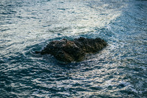aerial view over a rock in the ocean 