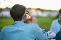 a man drinking from a mason jar at a dinner party 