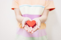 a boy holding a paper heart in cupped hands 