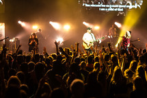 a band on stage surrounding by fans in the audience 
