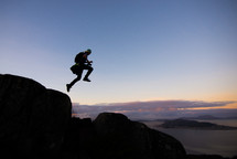 silhouette of a man jumping on a mountainside