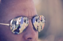 reflection of a crowd of people in a man's sunglasses 