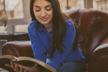 Woman sitting a chair reading the Bible.