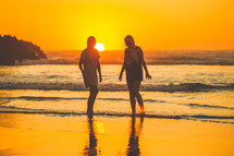 young women walking on a beach at sunset 