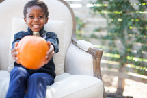 a child holding an orange pumpkin 