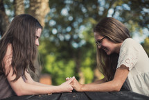 teen girls holding hands and praying