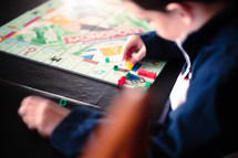 A boy plays with game pieces on a board game.