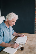 man writing in a journal after reading a Bible 