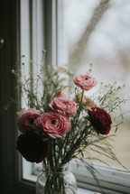 vase of pink and red flowers in a window 