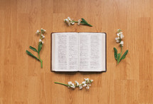 flowers and open Bible on a wooden table 