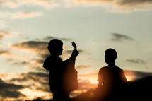 two boys worshipping God at sunset 