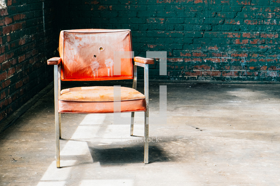 Chair in en empty room with brick walls.
