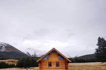 log cabin surrounded by mountains 