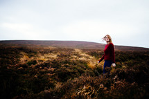 a woman walking on a hilly landscape 