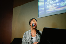 woman singing into a microphone at a worship service 