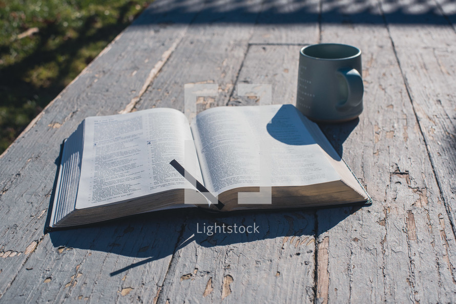 A Bible with a cup of coffee on a rustic back porch,.