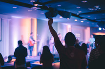 worship leaders on stage and raised hands in the audience 