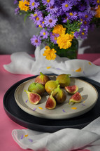 Plate of figs on table with flowers
