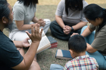 Group praying while sitting on ground