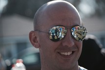 reflection of a crowd in a man's sunglasses 