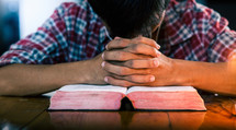 a man praying over a Bible 