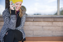 woman sitting on a bench, talking on a cellphone 
