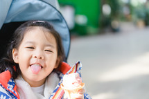toddler girl eating ice cream in a stroller 