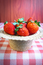 Fresh strawberries decorated on a straw hat. on a red picnic blanket.