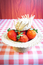 Fresh strawberries decorated on a straw hat. on a red picnic blanket.