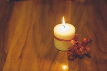 flame on a white candle wrapped in red ribbon