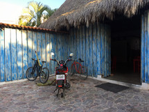 bikes parked in front of a thatched roof building 
