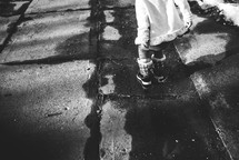 a child in snow boots standing on a sidewalk 