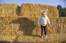 Little girl jumping in the hay