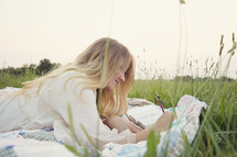 young woman reading on a blanket in the grass