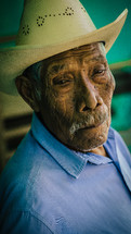 An elderly Hispanic man in a cowboy hat.